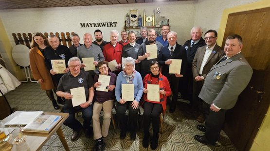 Gruppenbild mit sitzenden und stehenden Pesonen. Einige halten Urkunden.