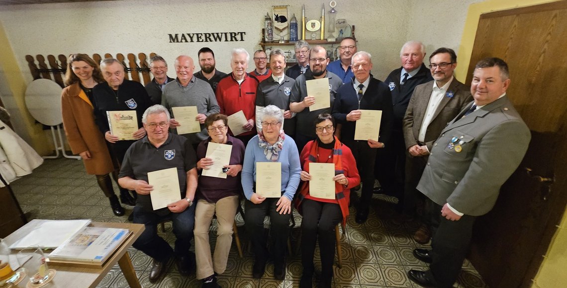 Gruppenbild mit sitzenden und stehenden Pesonen. Einige halten Urkunden.