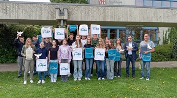 Schüler halten weiße und blaue Taschen mit Volksbund-Logo: Auszeichnung der Realschule Regenstauf für den zweiten Platz im Schülerwettbewerb.