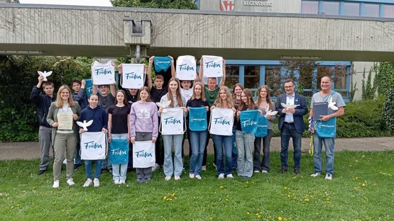 Schüler halten weiße und blaue Taschen mit Volksbund-Logo: Auszeichnung der Realschule Regenstauf für den zweiten Platz im Schülerwettbewerb.